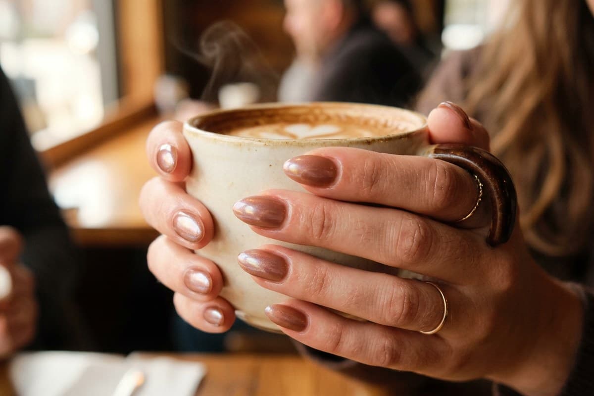 Glazed chocolate donut nails: sheer cocoa base with a pearl chrome glow on short almond nails