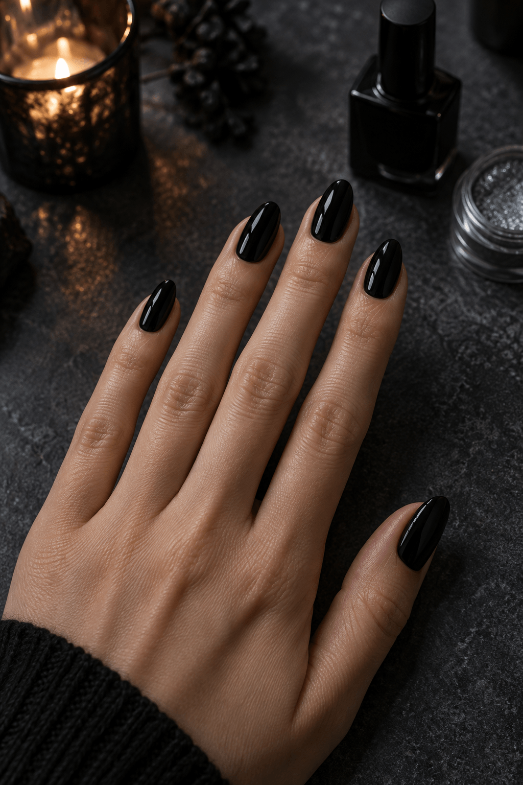 Glossy black almond nails prepared beside a chrome powder jar