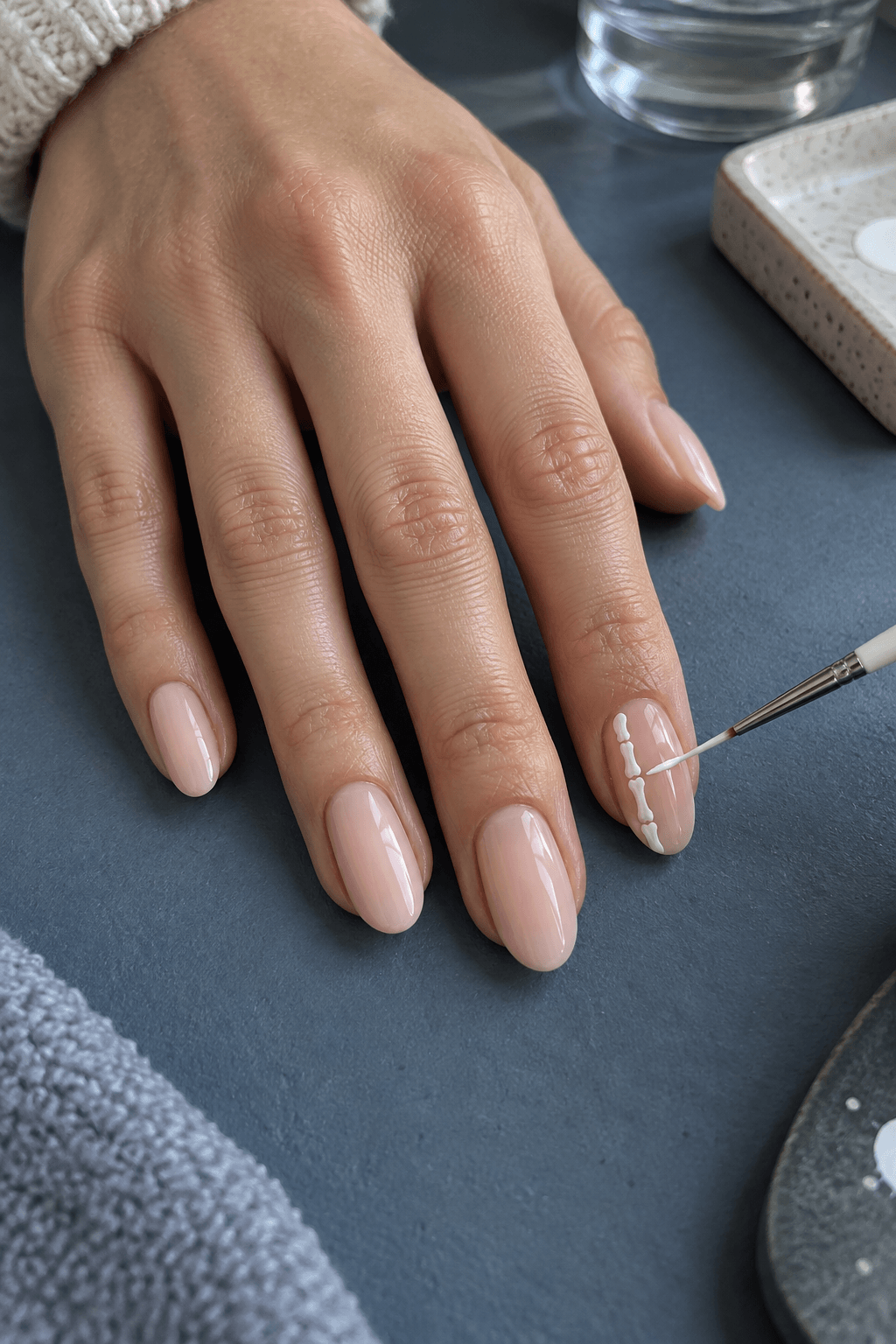 Fine white liner painting segmented finger bones across one nude accent nail