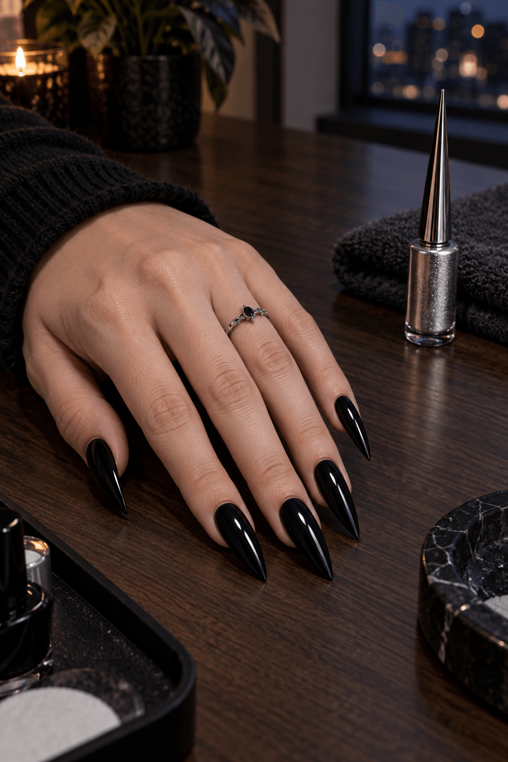 Glossy black stiletto nails prepared on a dark wood manicure table