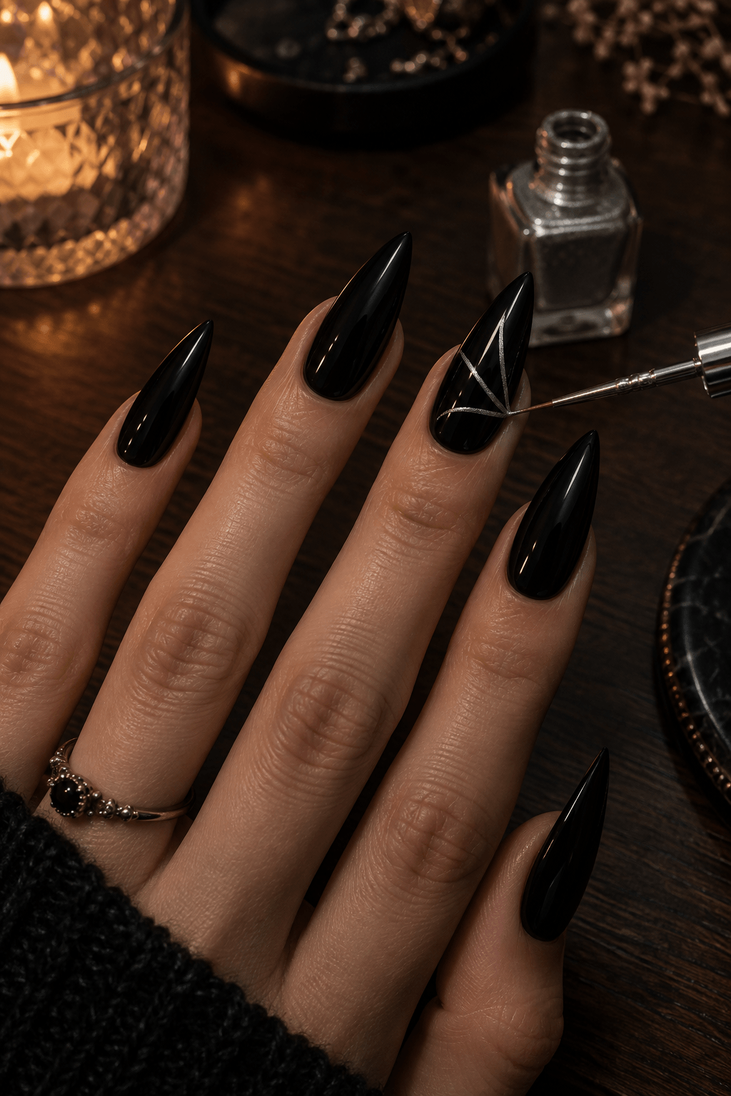 Fine silver liner drawing the first spiderweb spokes on a glossy black stiletto nail